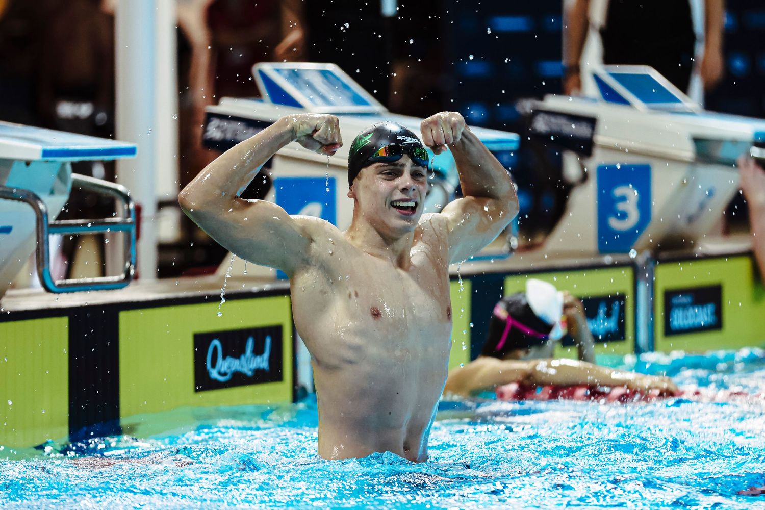Three athletes pose with medals in front of a swimming championships sponsorship backdrop.