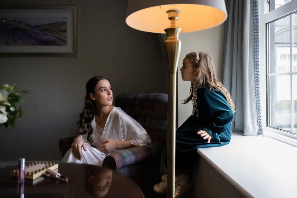 Two people relax in a cozy living room near a window with a floor lamp providing warm illumination.