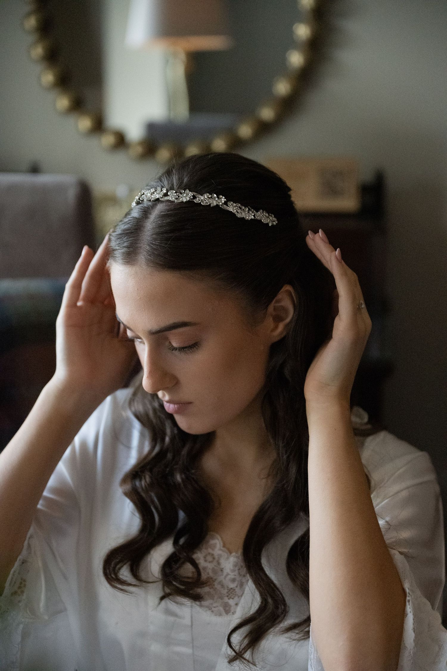 Side profile of bride wearing delicate crystal headpiece with flowing dark wavy hair on wedding day.