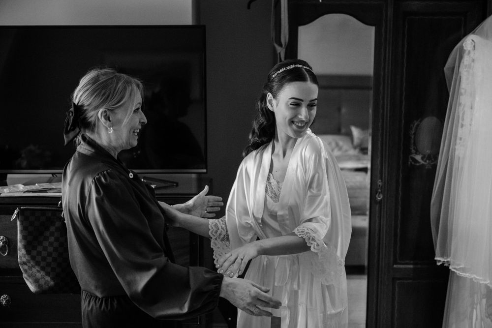 A black and white photograph shows an interaction between two people in a dressing room setting.