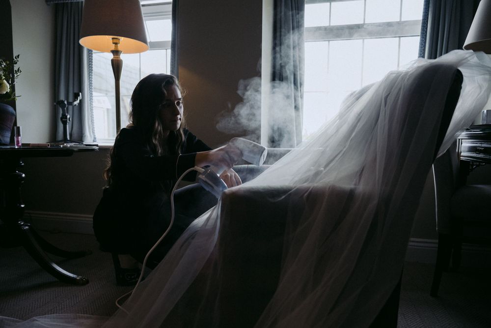 A person sits in a dark moody room with vapor or smoke illuminated by window light in a cinematic atmosphere.