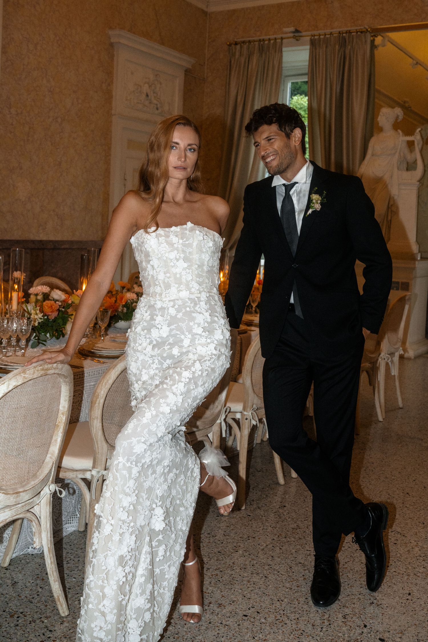 A couple walking through an elegant dining room at their wedding celebration.