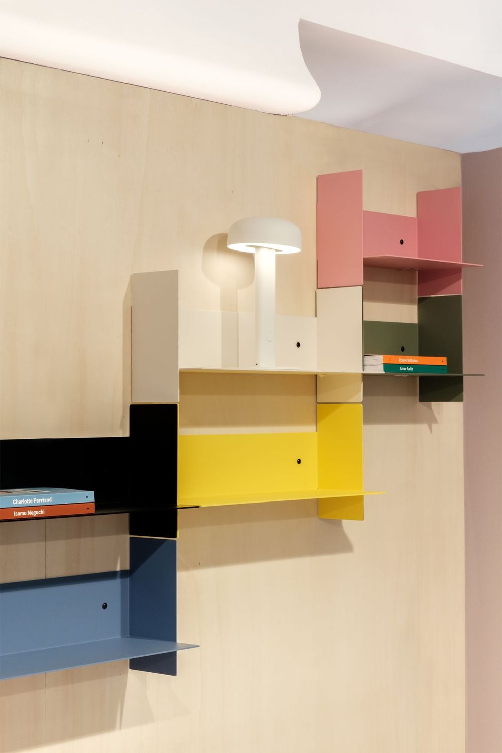 Colorful geometric wall shelving system with pink, yellow, and blue panels.
