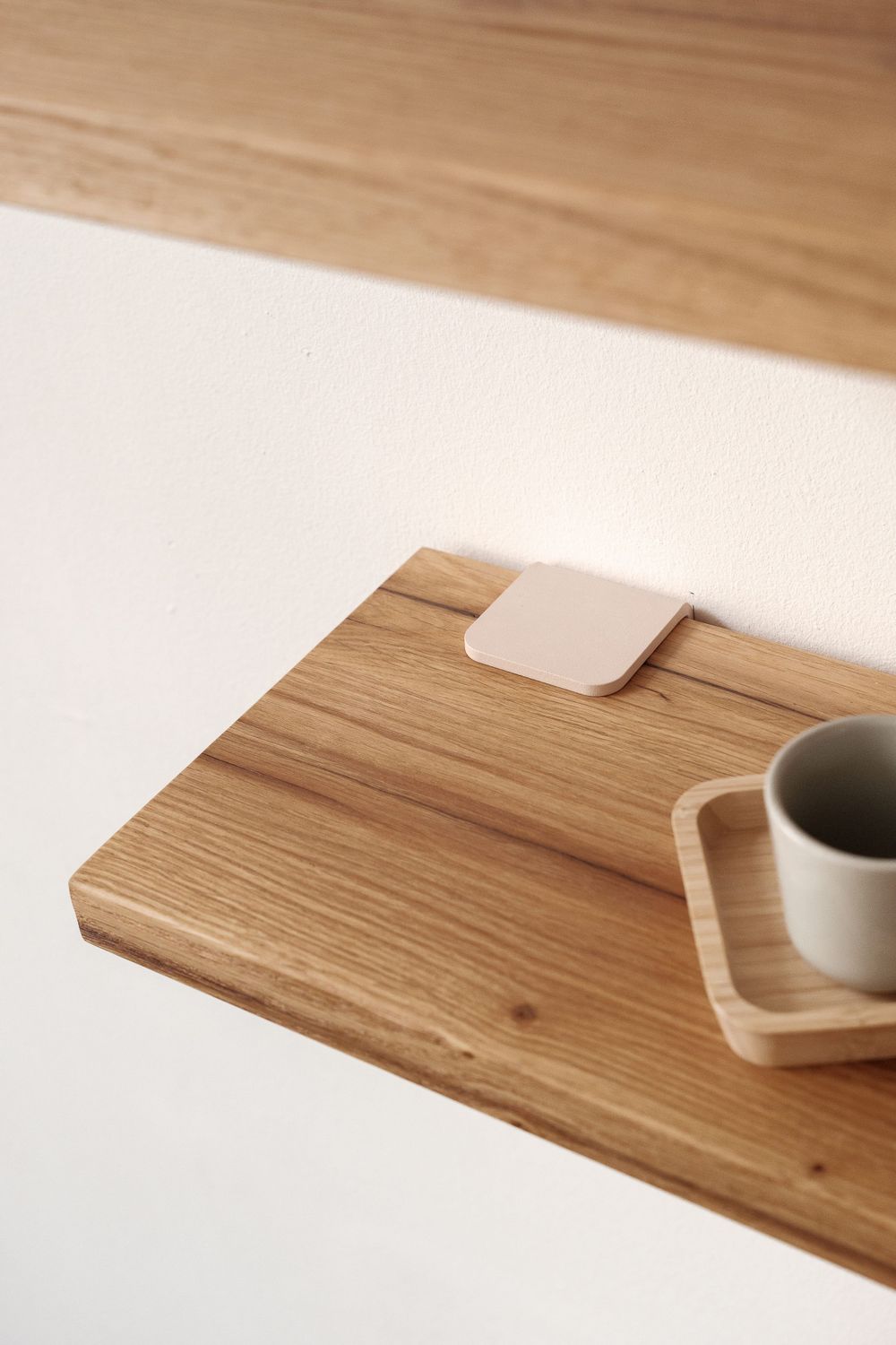 Wooden desk corner with ceramic coffee cup on minimalist coaster.