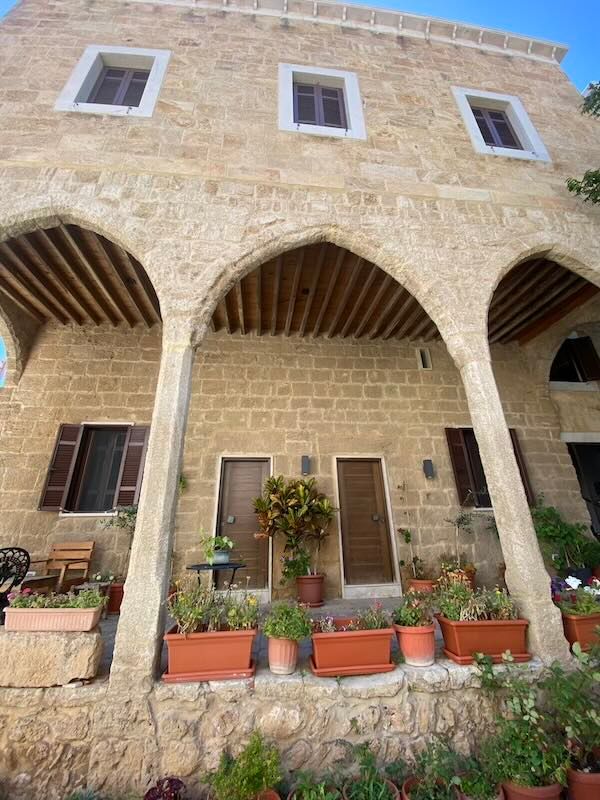 Traditional Mediterranean stone building with arched colonnade and potted plants decorating the entrance.