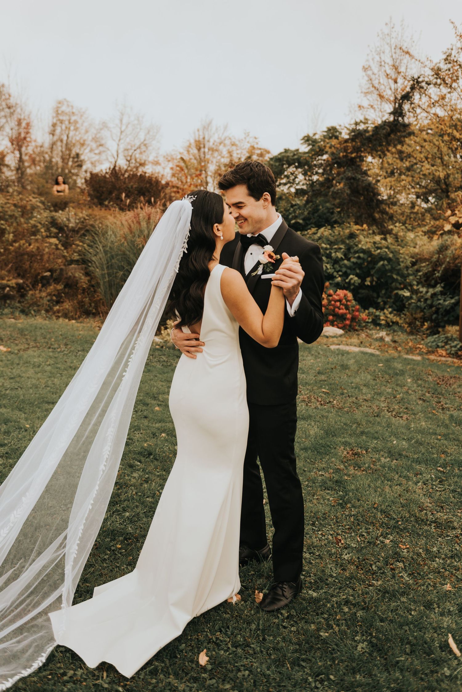 A couple shares their first dance outdoors during a romantic autumn wedding ceremony.