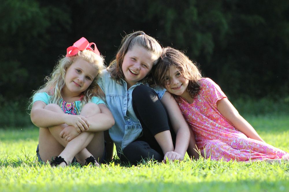 A series of outdoor portrait photos showing people laying in green grass on a sunny summer day.