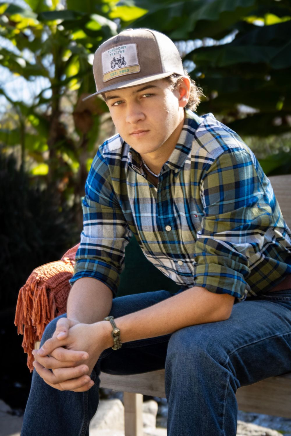 Casual outdoor portrait featuring youth in plaid shirt and baseball cap relaxing outside.