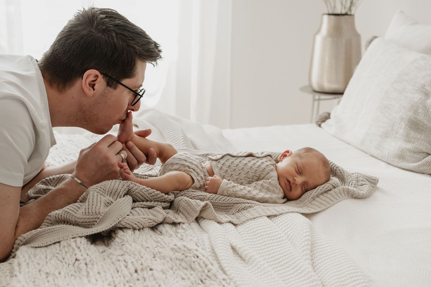Papa küsst zärtlich das Füßchen seines Babys beim Newbornfotoshooting Wien Stockerau Korneuburg, Tulln