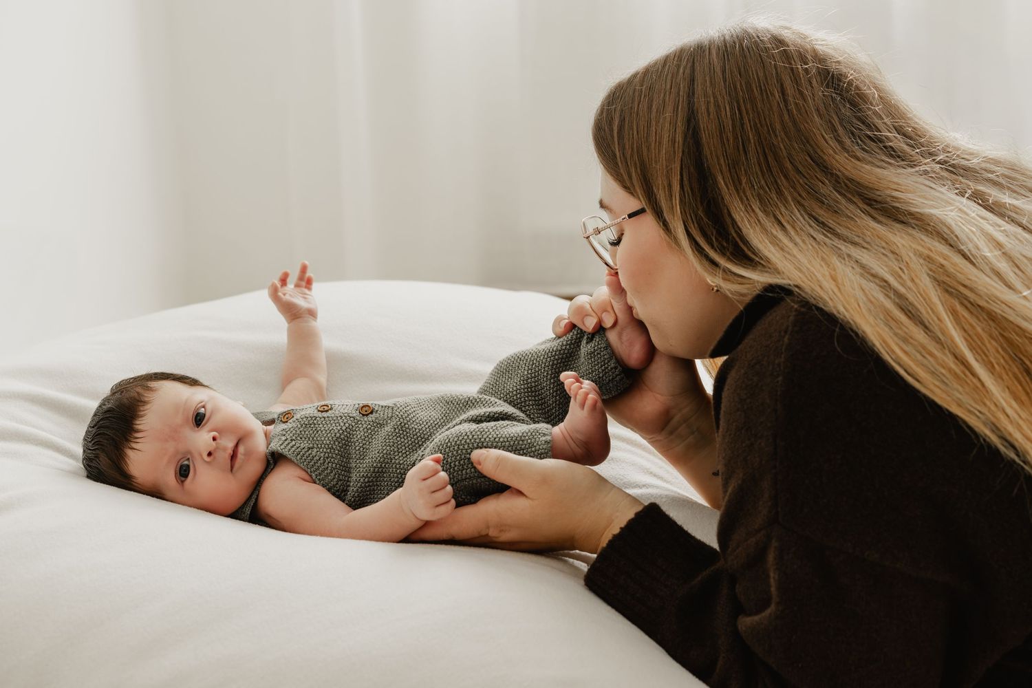 Mama küsst zärtlich das Füßchen ihre Neugeborenen beim Premiumbabyfotoshooting Stockerau