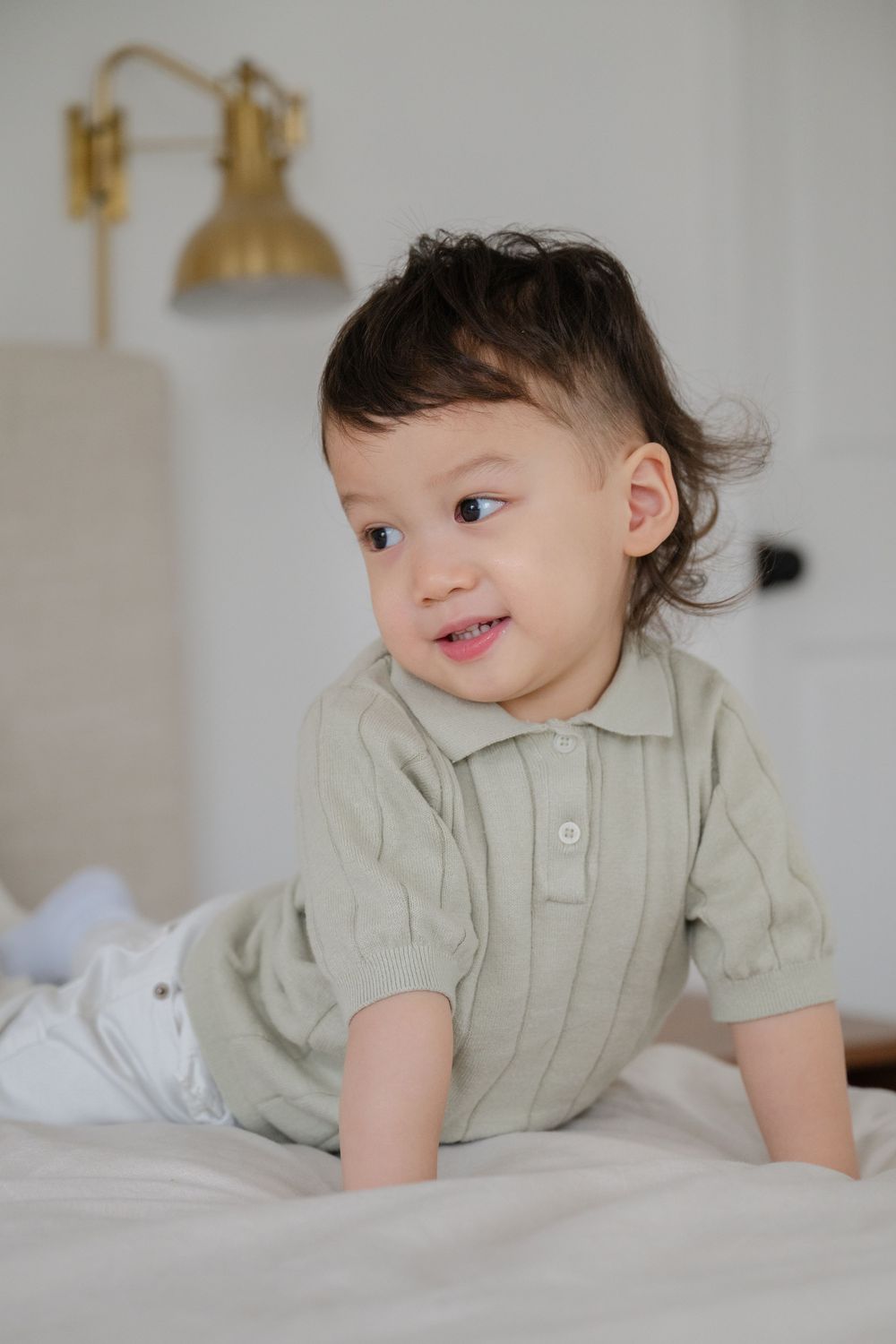 Toddler smiling playfully on the bed during family photo session by Phoebe Lee Photo of Toronto, Ontario