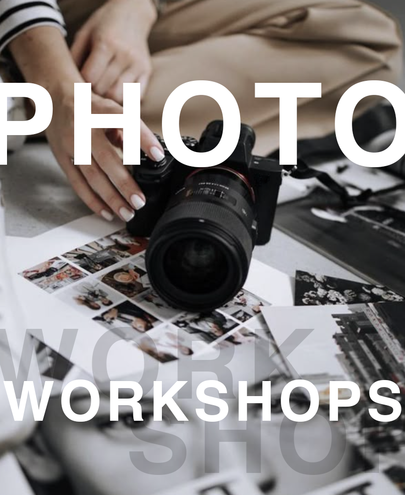 Photography workshop setup with a DSLR camera lens and printed photos scattered on a gray desk surface.