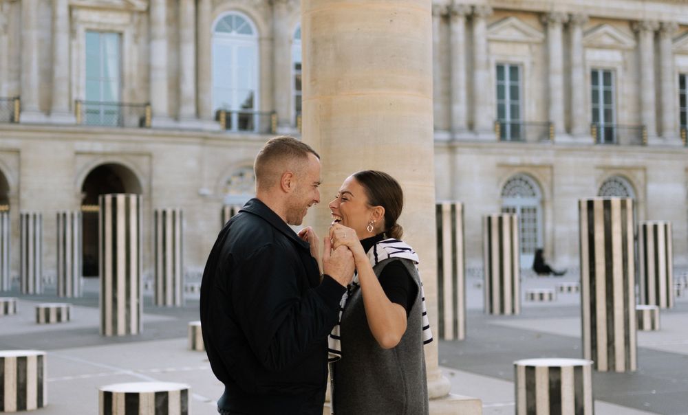 Couple shares a romantic moment among the Buren Columns at Palais Royal in Paris, France.