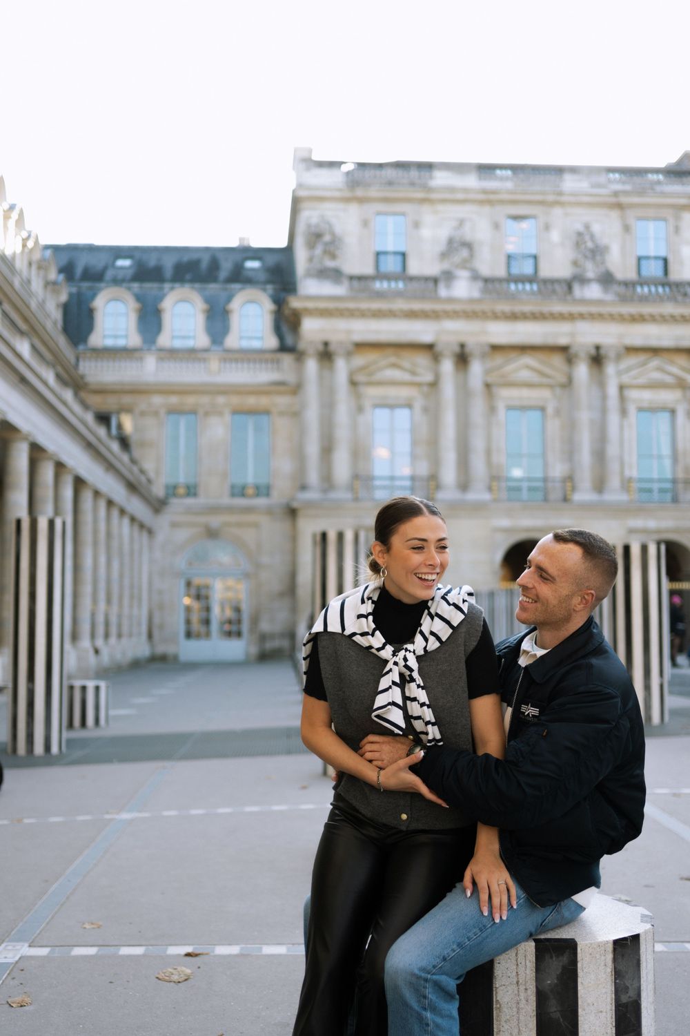 Couple sharing a romantic moment together at the Royal Palais in Paris with classical architecture in background.