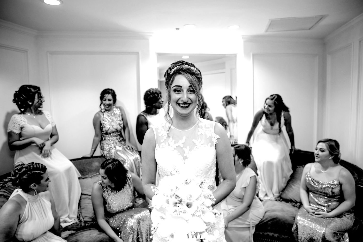 Black and white wedding preparation scene with laughter and joy in a bright room.