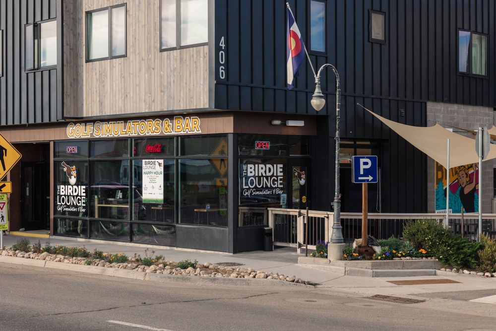 Modern restaurant storefront with black vertical siding and large windows on a street corner.