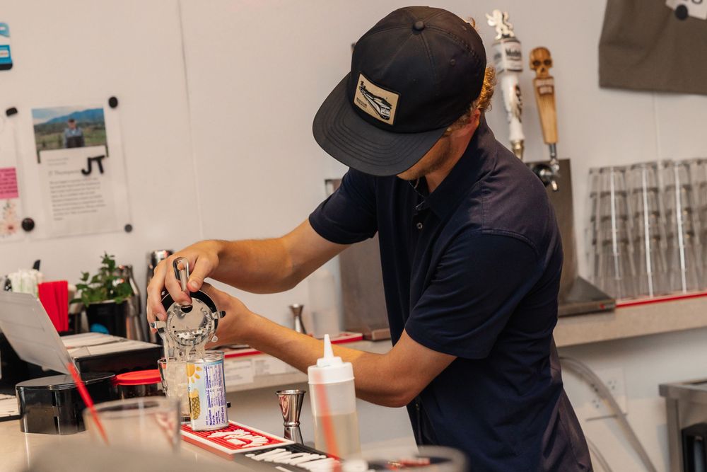 Restaurant worker preparing drinks behind a bar counter.