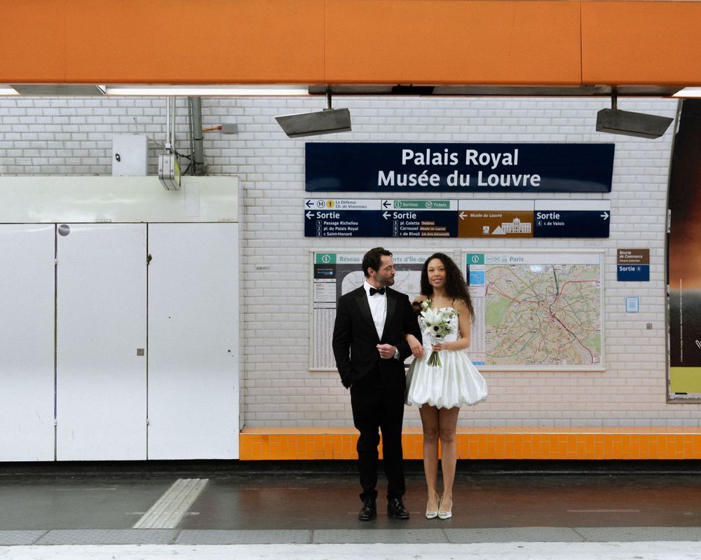 A couple in wedding attire poses at the Palais Royal-Musee du Louvre metro station in Paris.