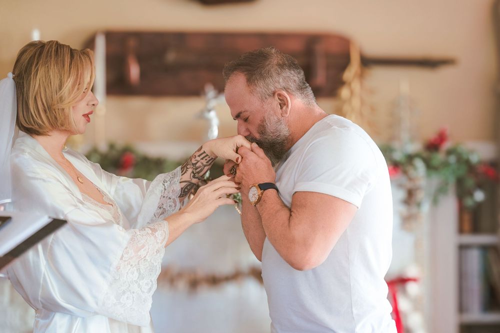 Couple sharing an intimate moment during a romantic Christmas photoshoot in a cozy home setting.