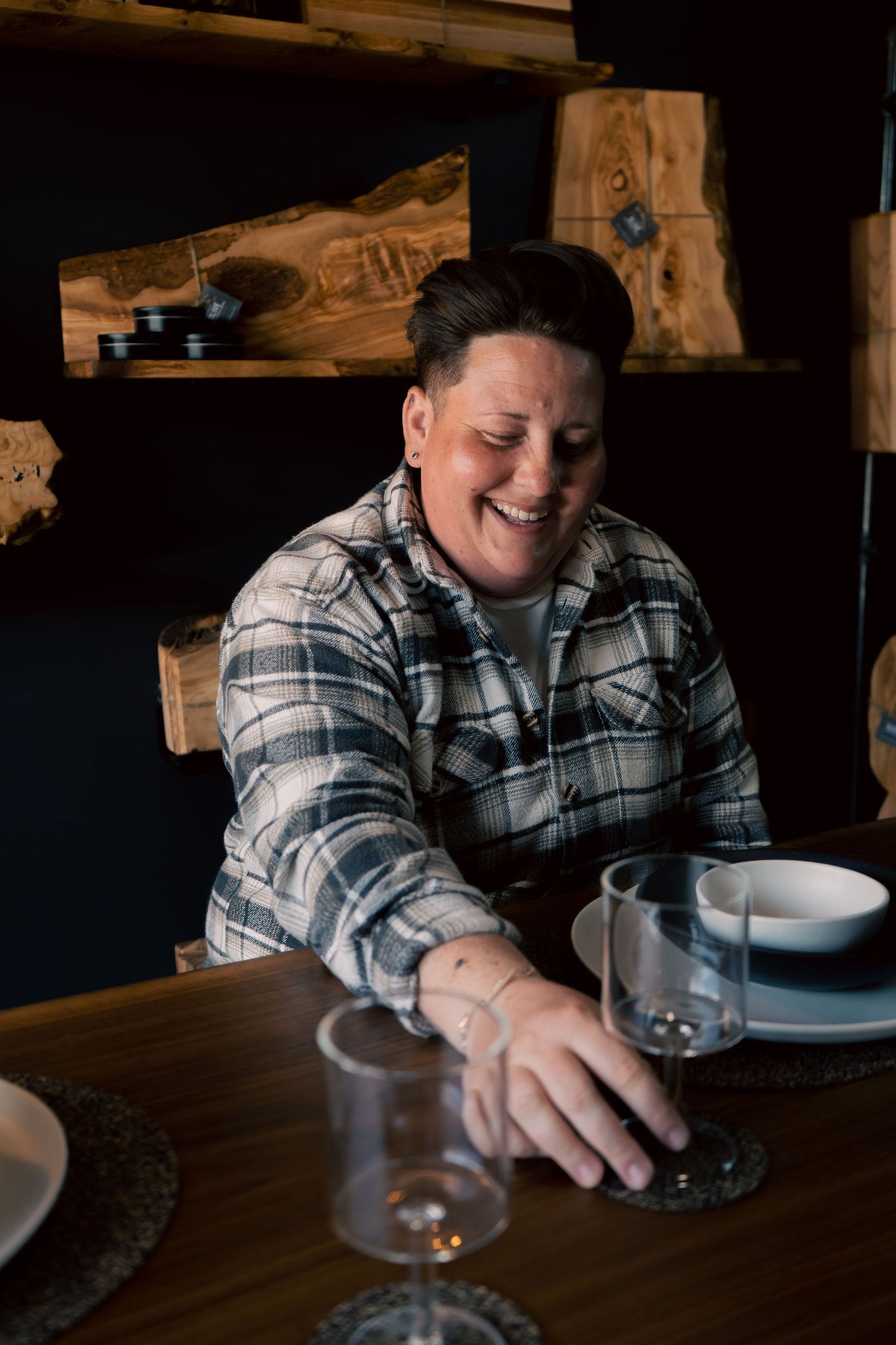 branding portrait of business owner sat at a handmade table holding tableware in a dark retail hut on Folkestone Harbour Arm, Kent