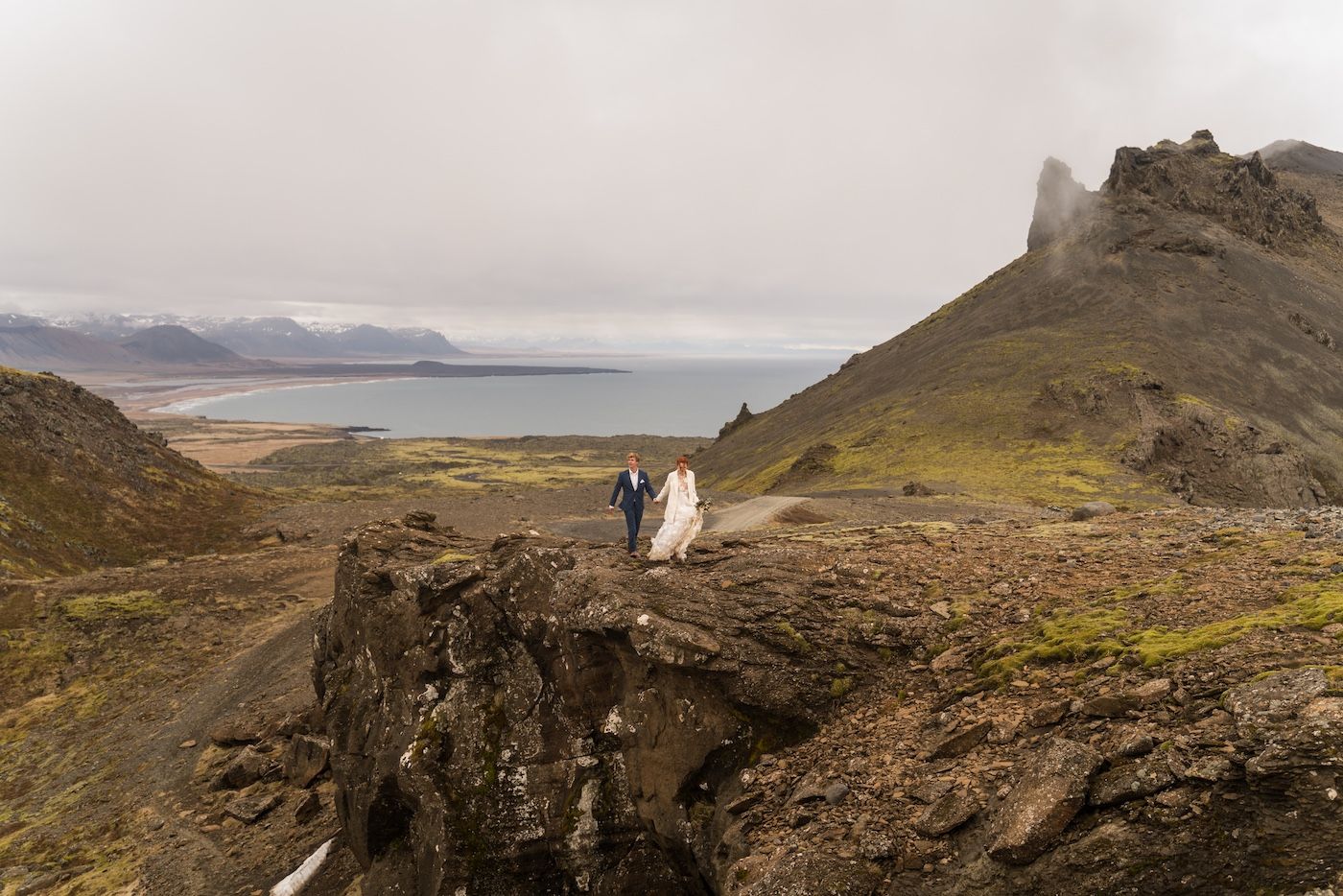Couple walking hand in hand on a cliff in Snaefellsjokull