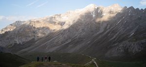 Panoramic view of snow-dusted mountain peaks under a bright blue sky in the Alps.