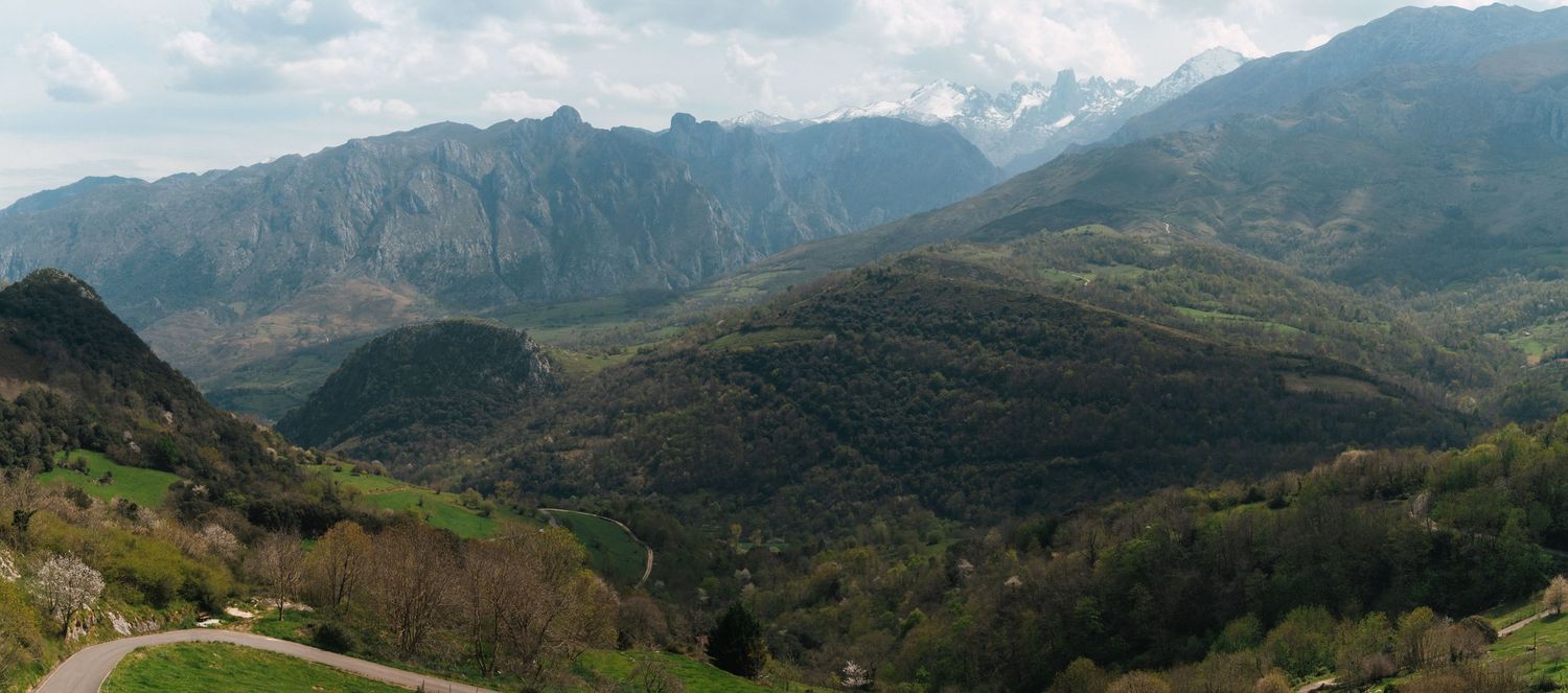 Panoramic view of mountain ranges with green valleys and distant peaks.