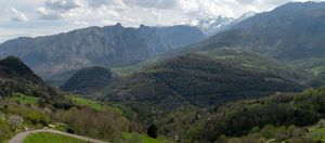 Rolling green mountains and valleys stretching to distant peaks under cloudy sky.
