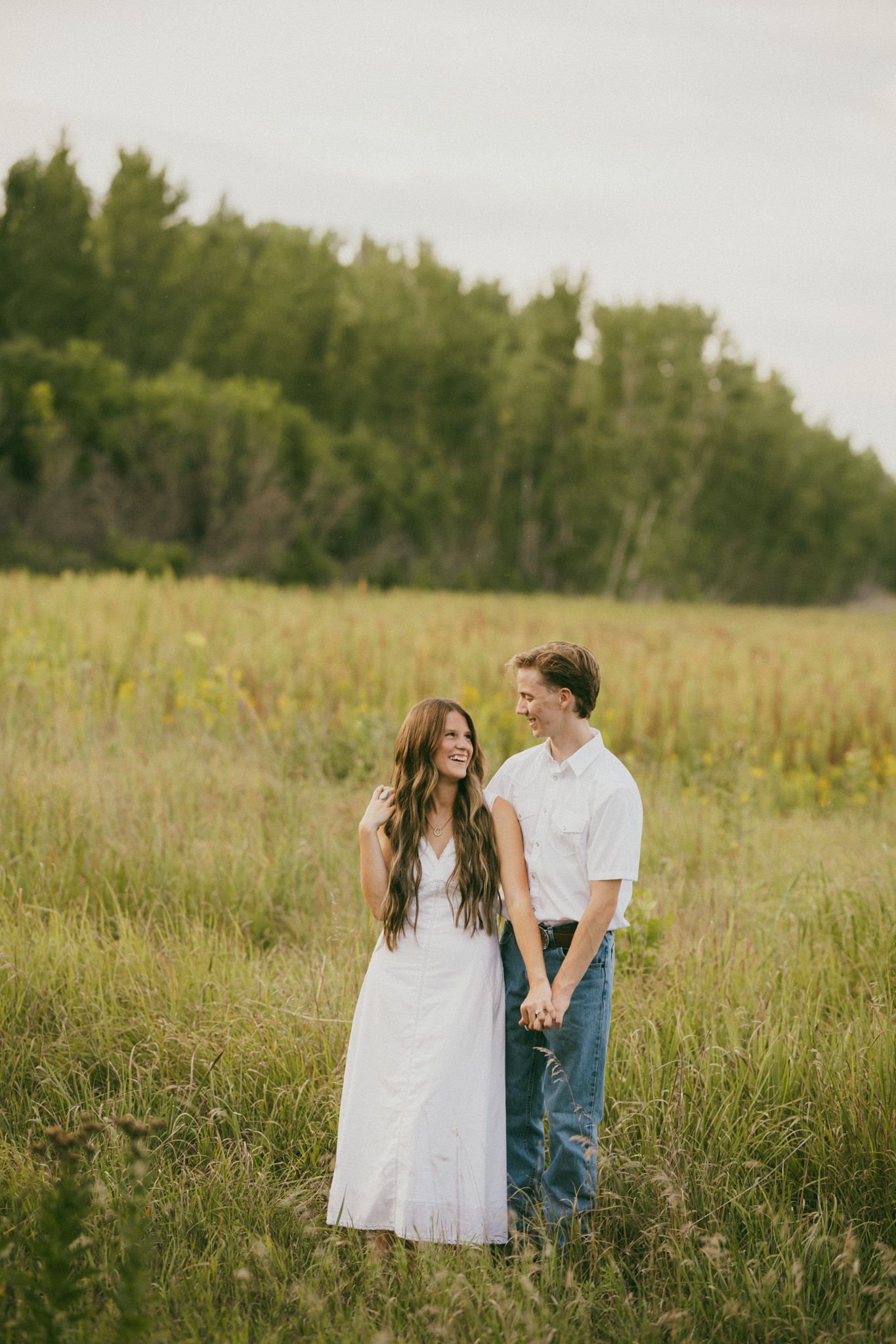 Couple sharing intimate moment in green field at sunset.