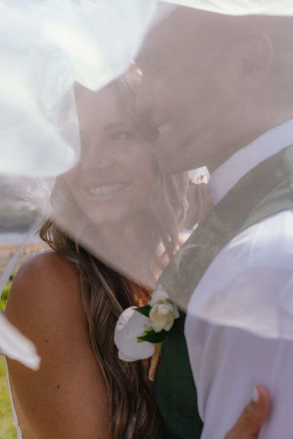 Two people sharing an intimate moment through a soft dreamy veil at an outdoor wedding ceremony.