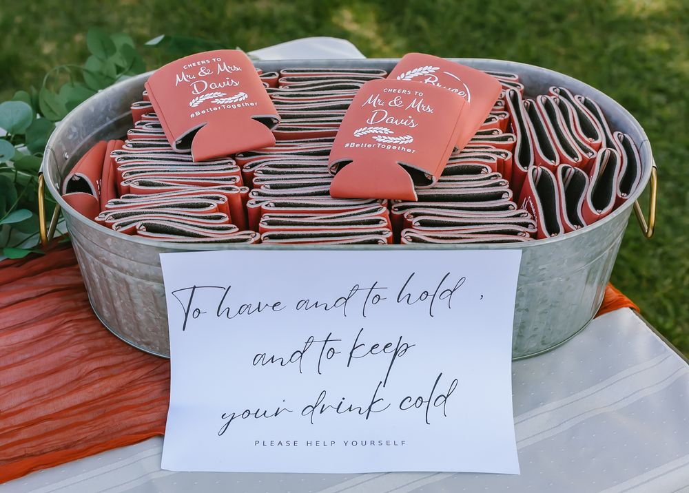 Coral wedding koozies and a handwritten note displayed in a galvanized metal tub for drink service.