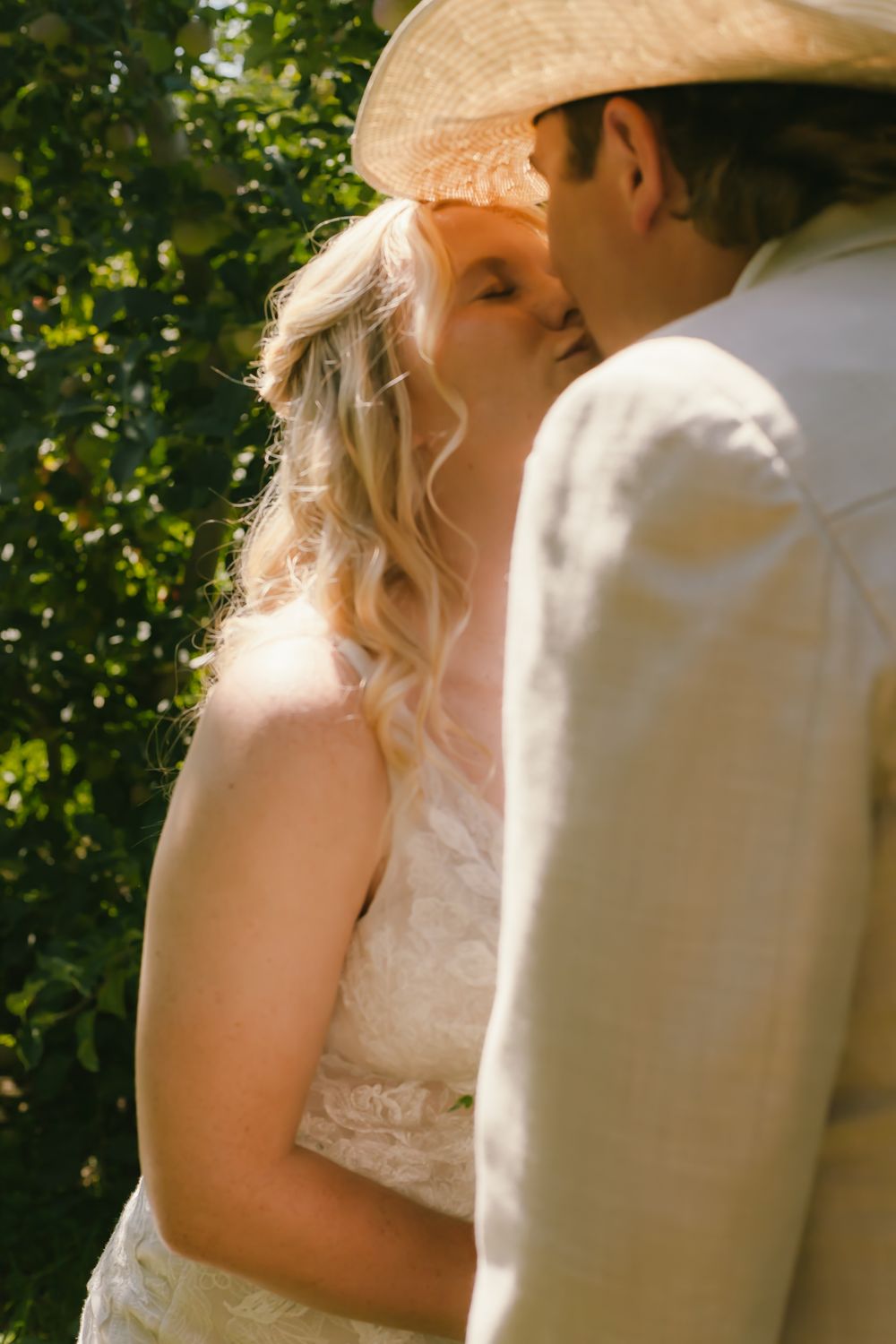 A romantic moment between a couple outdoors, with sunlit greenery in the background.