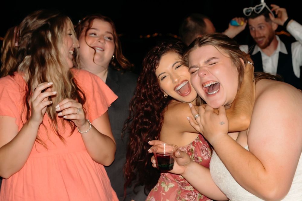 A group of friends laugh joyfully together at a nighttime party gathering.