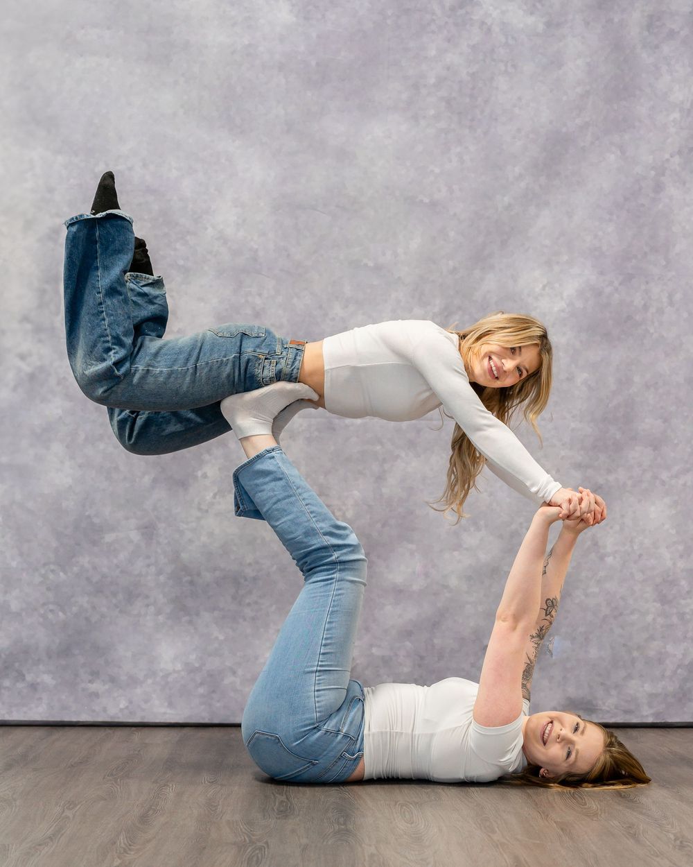 Creative acrobatic pose with two performers in jeans and white tops.