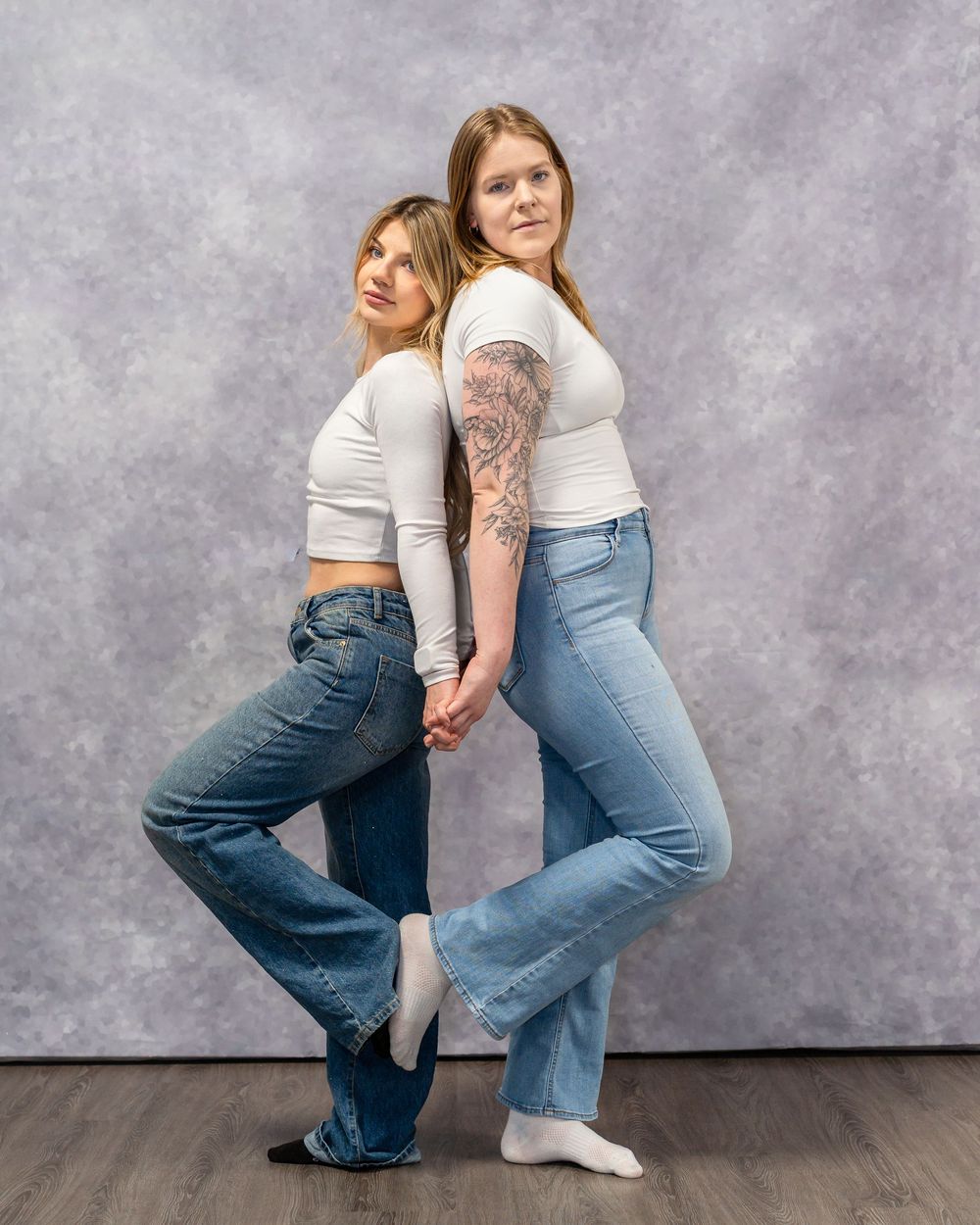 Fashion models in coordinated outfits pose together against gray studio background.