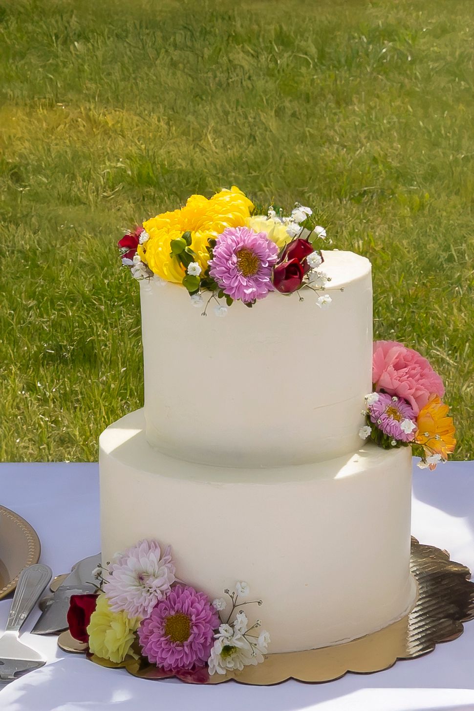 2 tier wedding cake with off white fondant and fresh spring flowers made by Crystal with Rose Hill Bakery