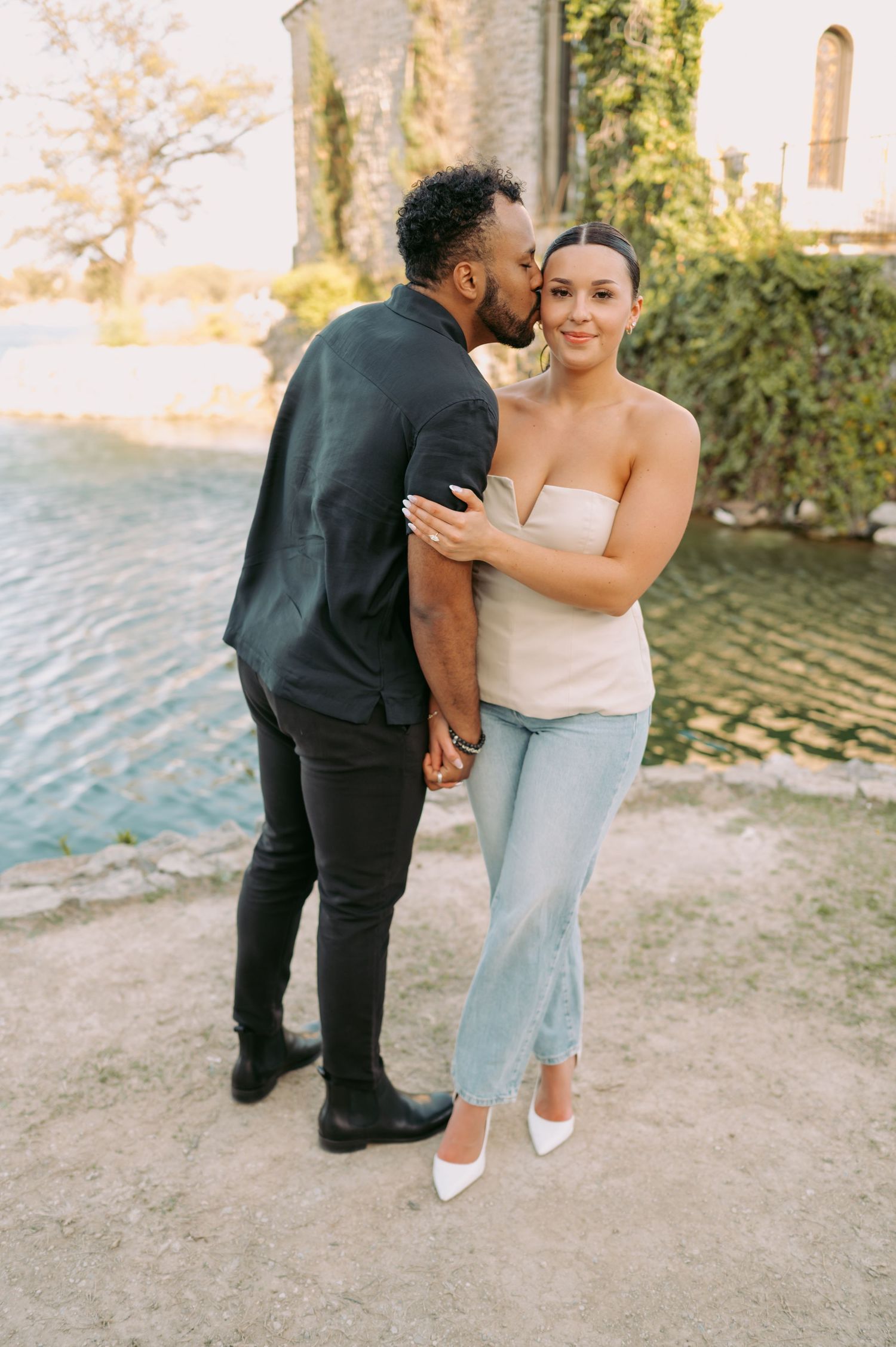 A couple shares an intimate moment during their engagement photoshoot by the water.