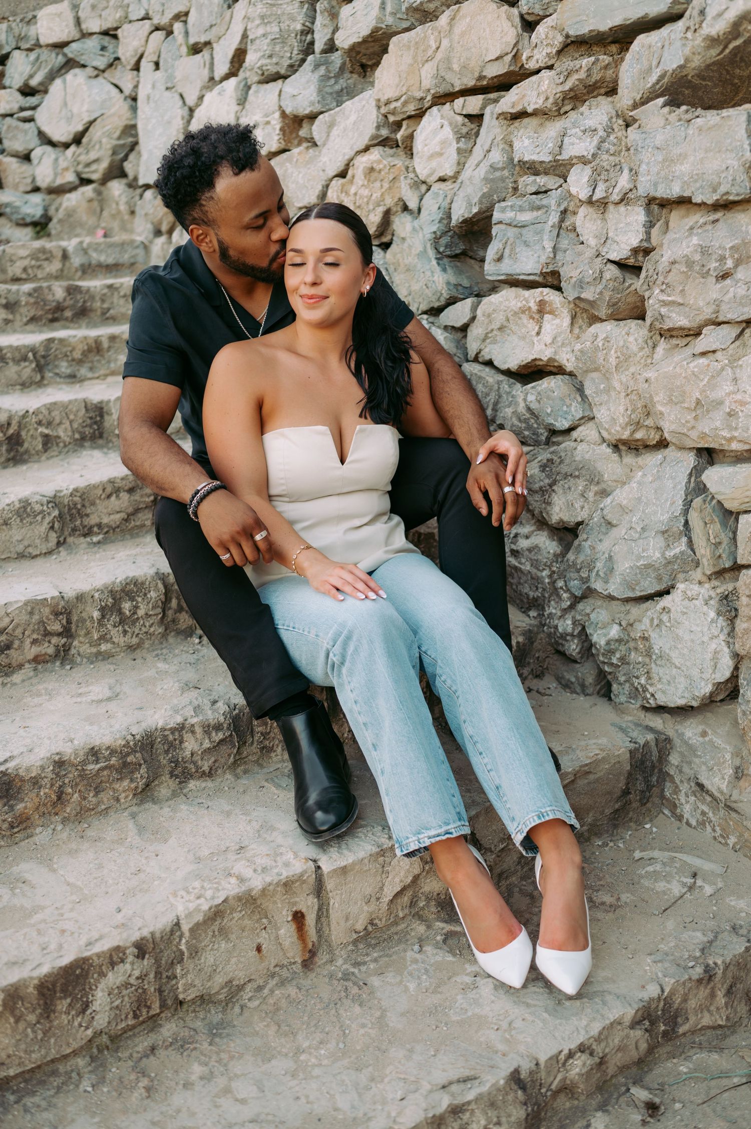 A couple poses on stone steps during a romantic photoshoot.
