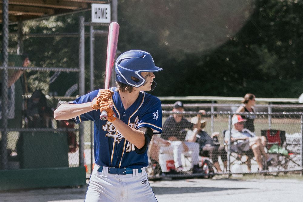 Baseball player in navy uniform stands at bat with focused stance during outdoor game.