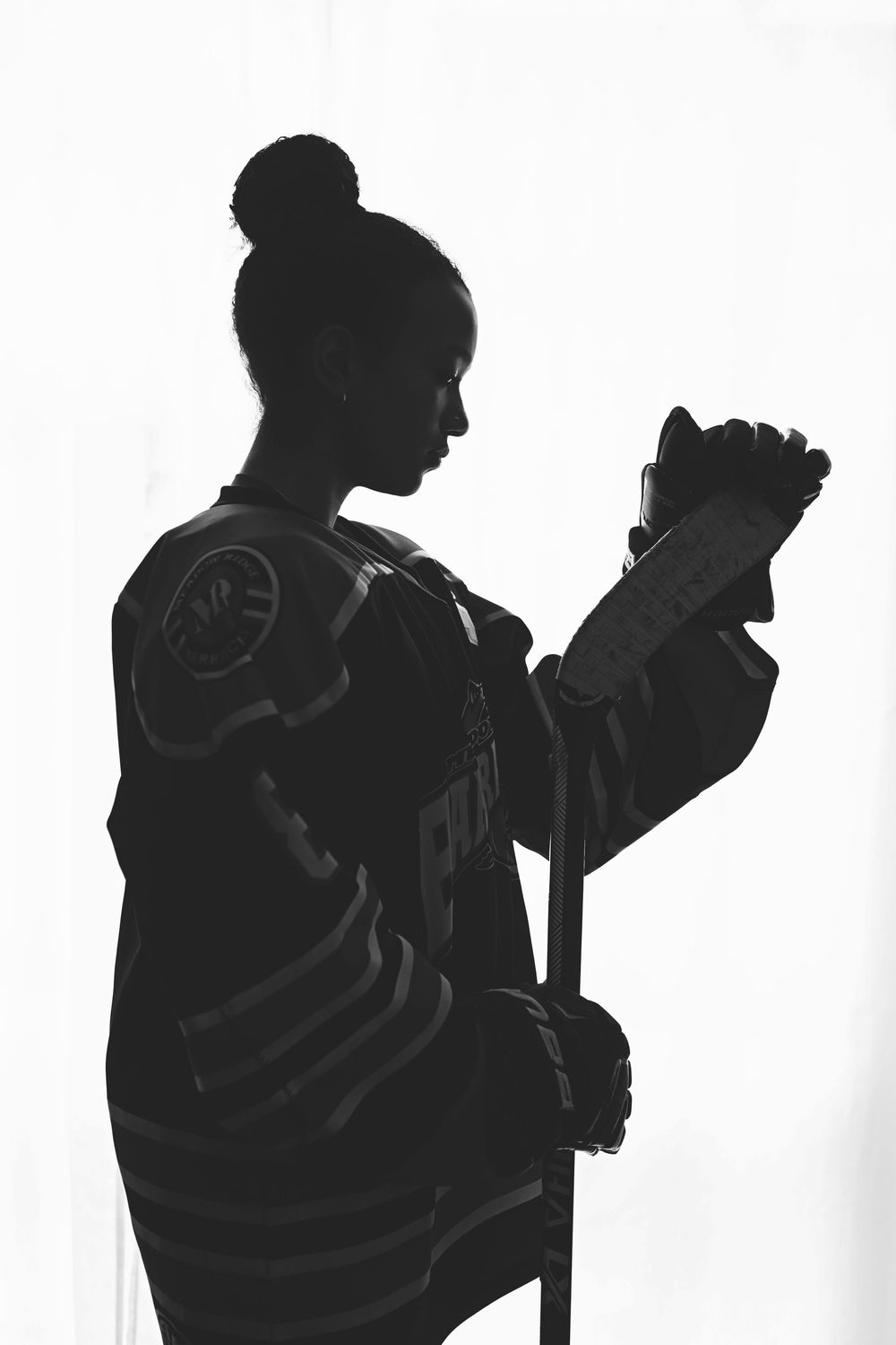 Black and white silhouette of a figure with a bun hairstyle holding a microphone in performance stance.