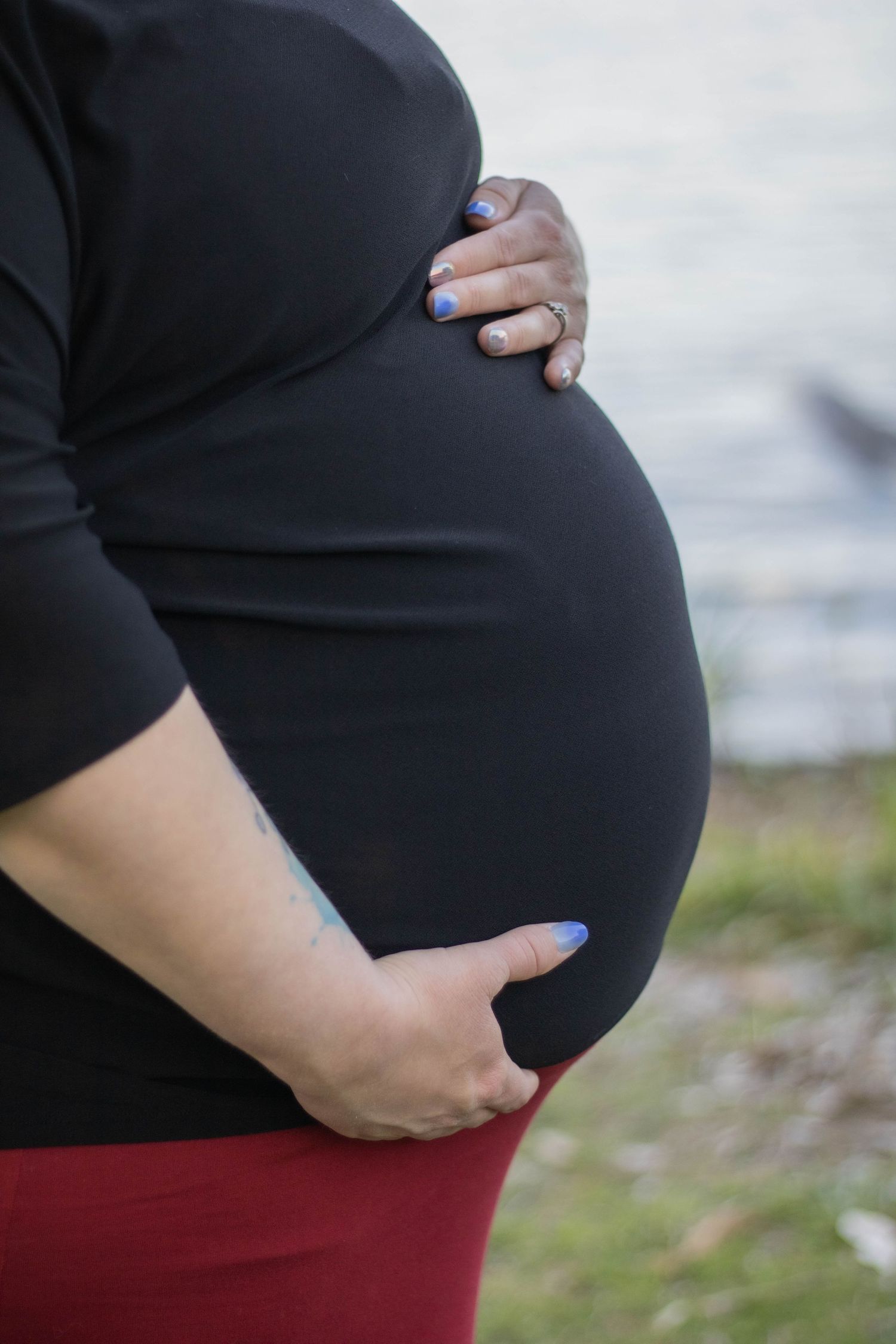 Close-up of pregnant belly with hands gently cradling the bump.