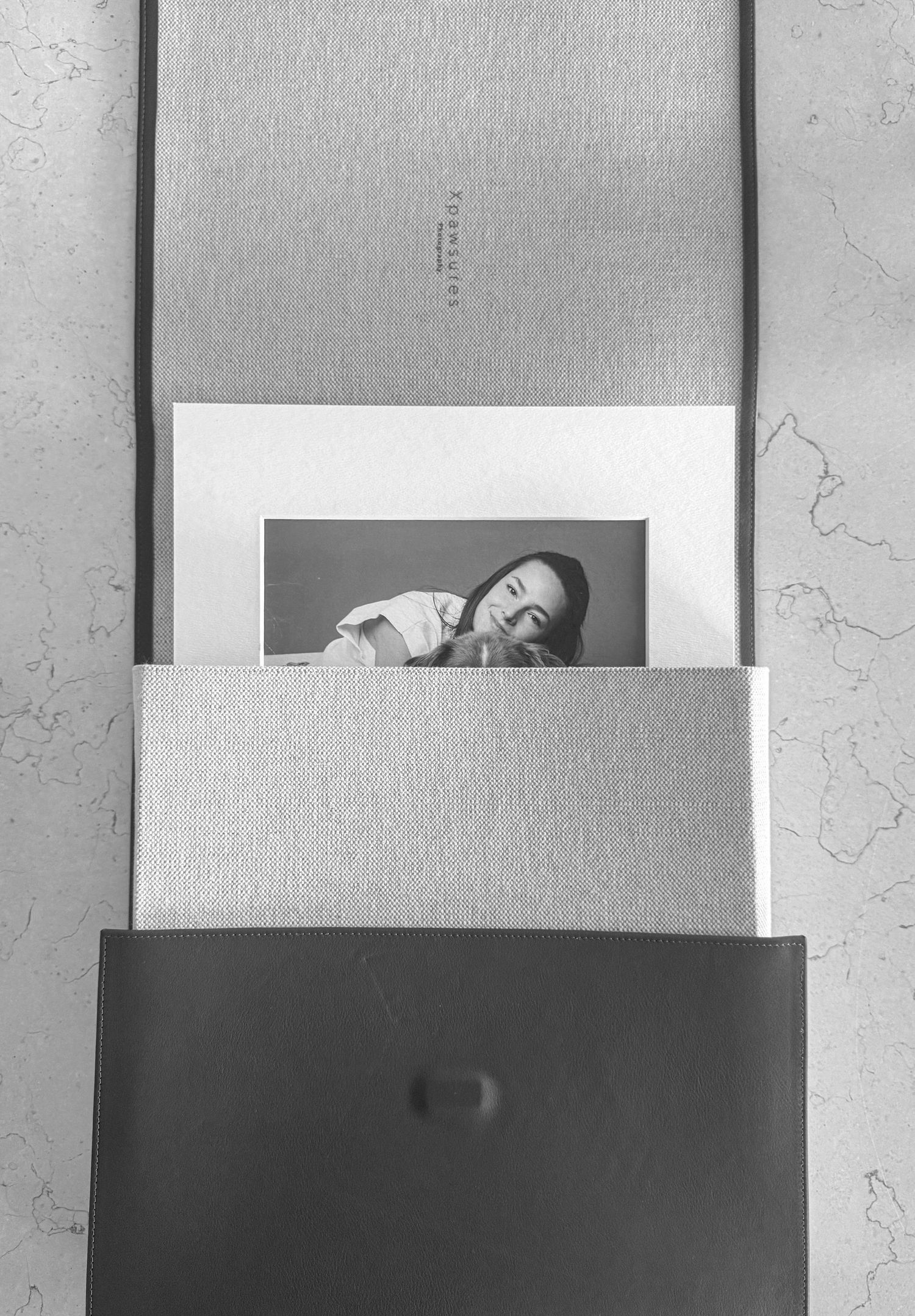 Black and white layered artistic photo composition showing white frames and paper arrangements against a textured background.