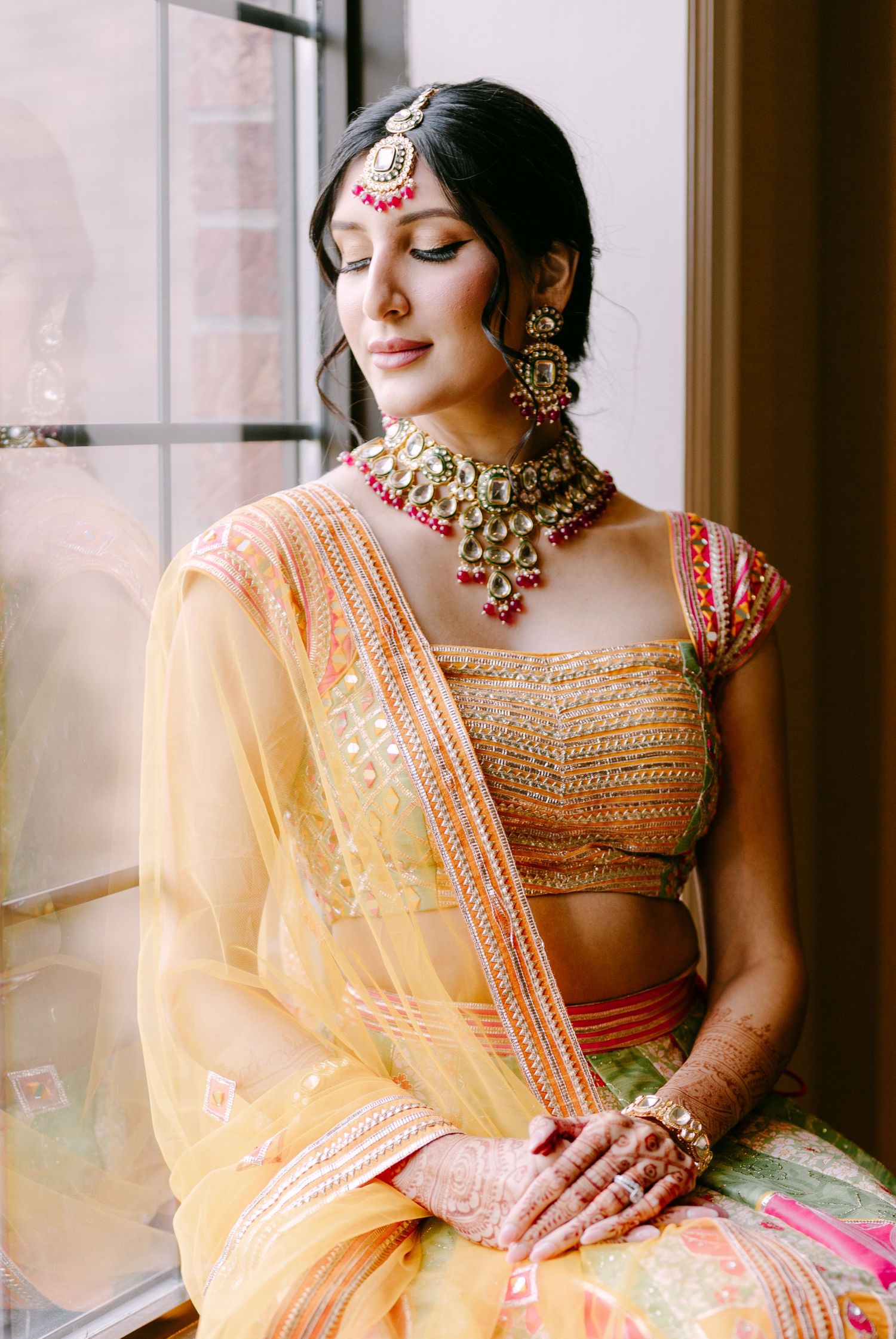 Traditional Indian bridal attire in peach with ornate gold jewelry and embroidered details.