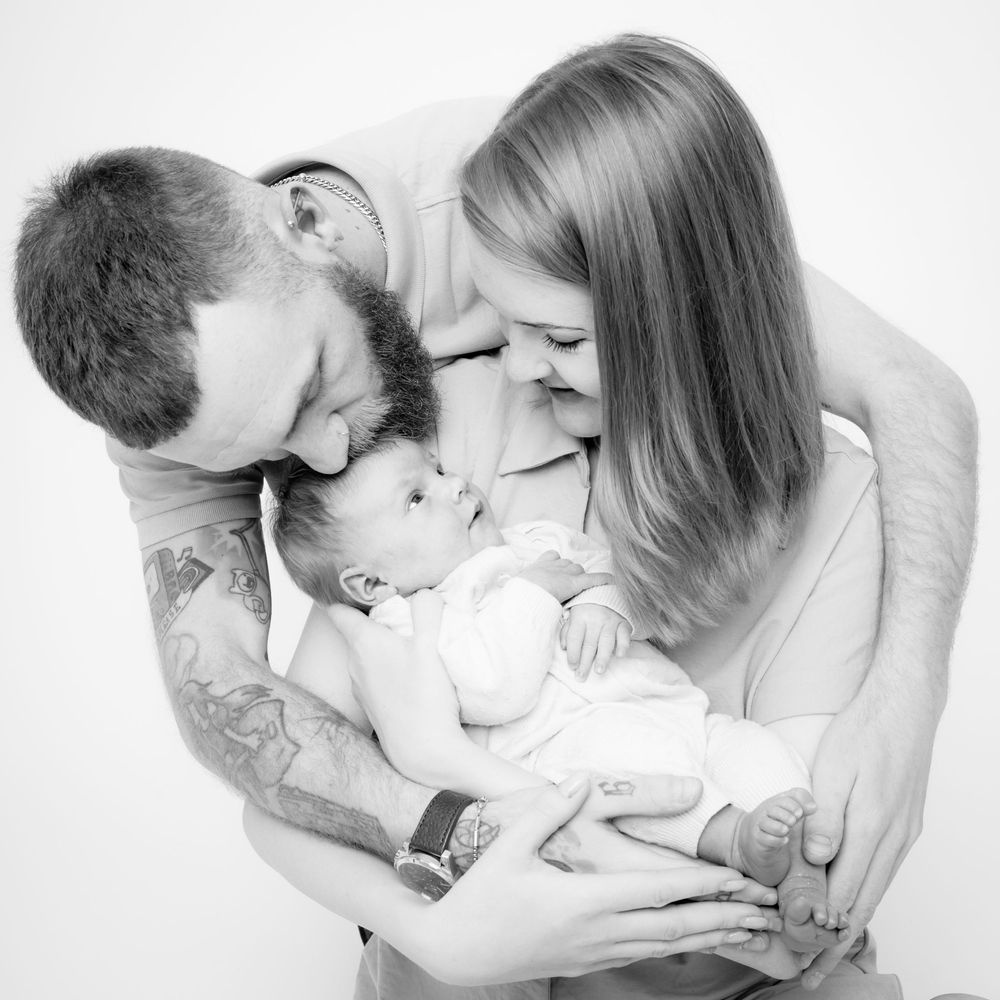 Father gazing lovingly at his newborn baby during a relaxed photo session Newborn photography by Abigail's Studio