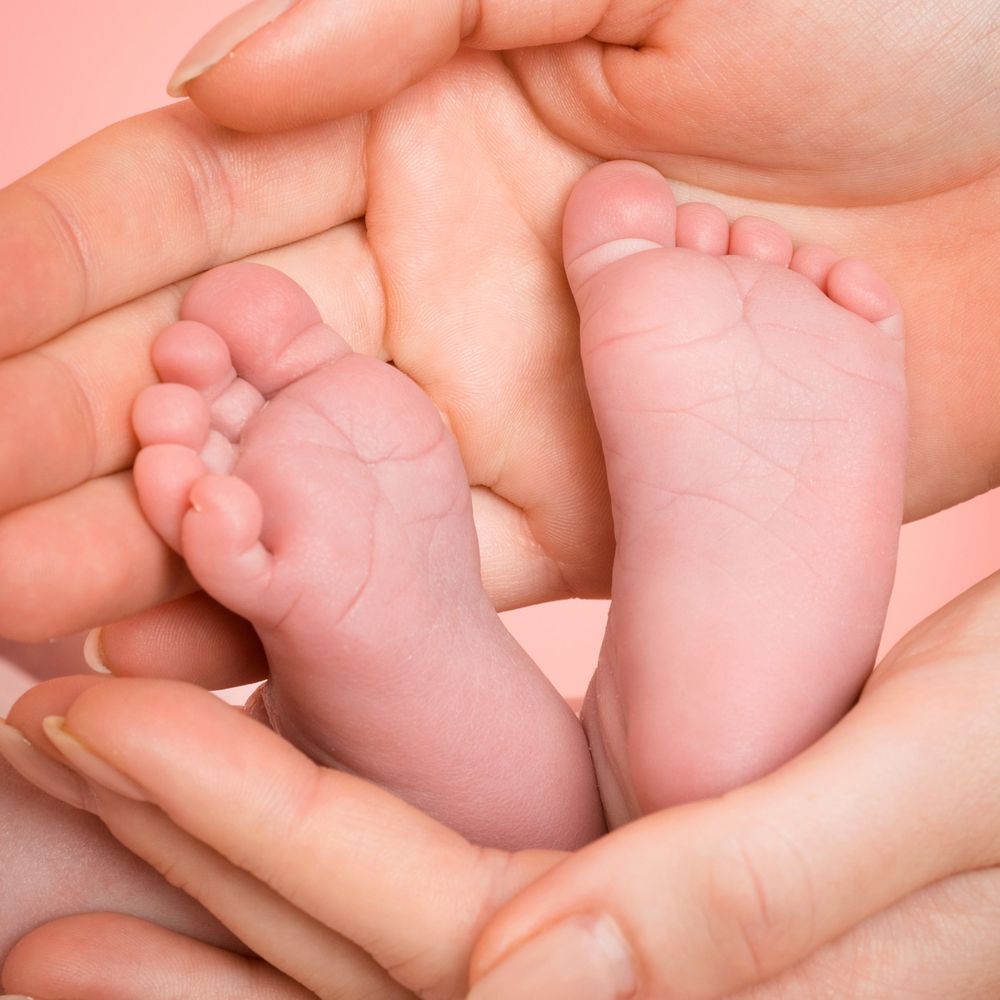 Tiny newborn feet resting in a parent’s hands Newborn photography in Buckingahamshire by Abigail's Studio