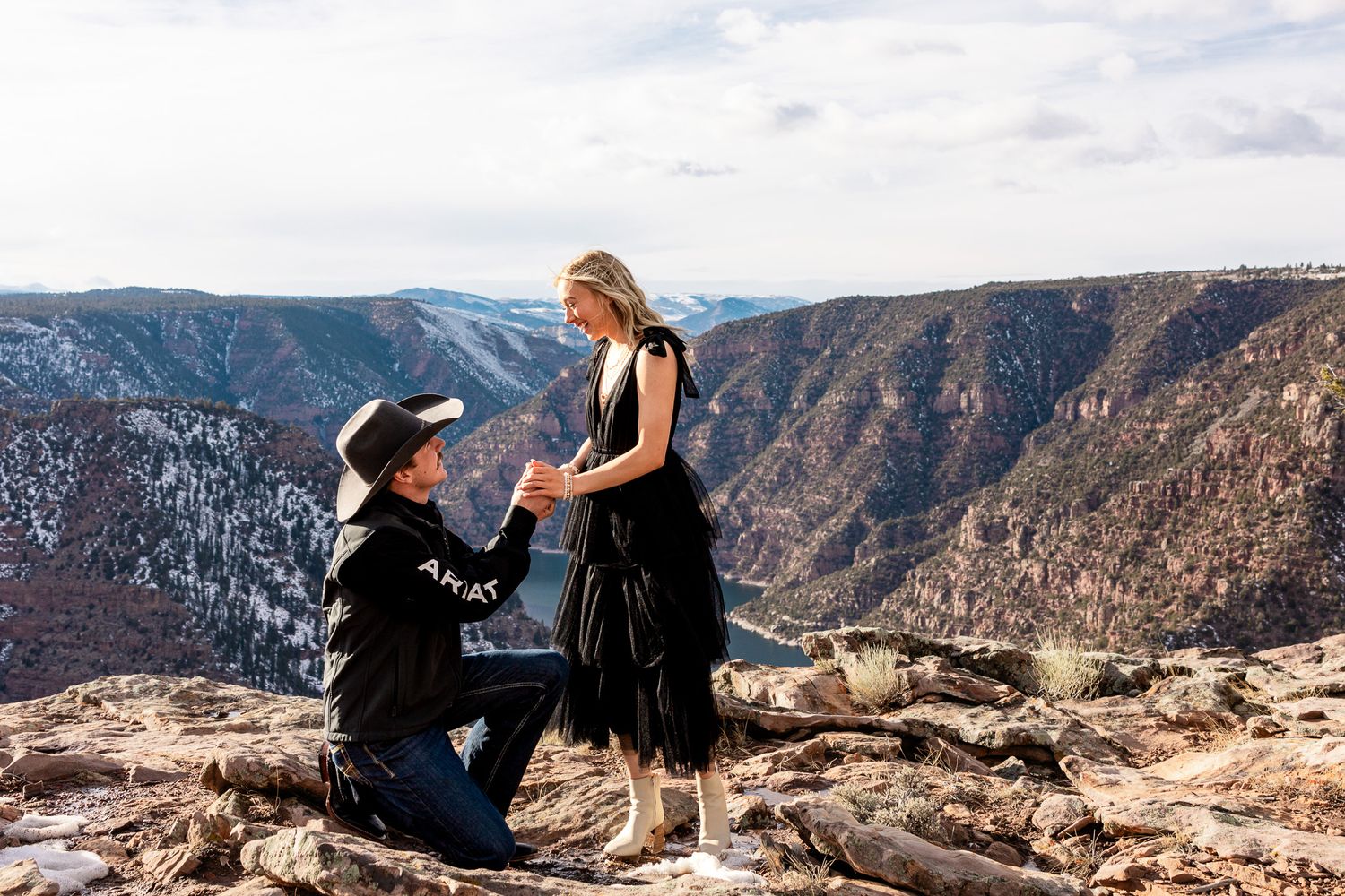 Utah Proposal Photoshoot
Two people huddle together on a rocky cliff overlooking a snow-dusted canyon under cloudy skies.