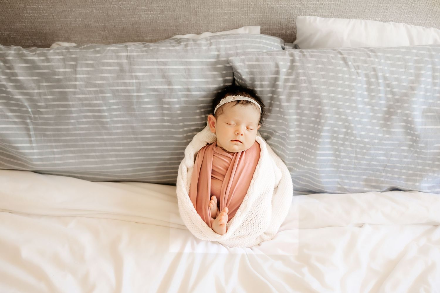 A newborn baby sleeps on the bed as an Honolulu Newborn Photographer photographs a newborn session.
