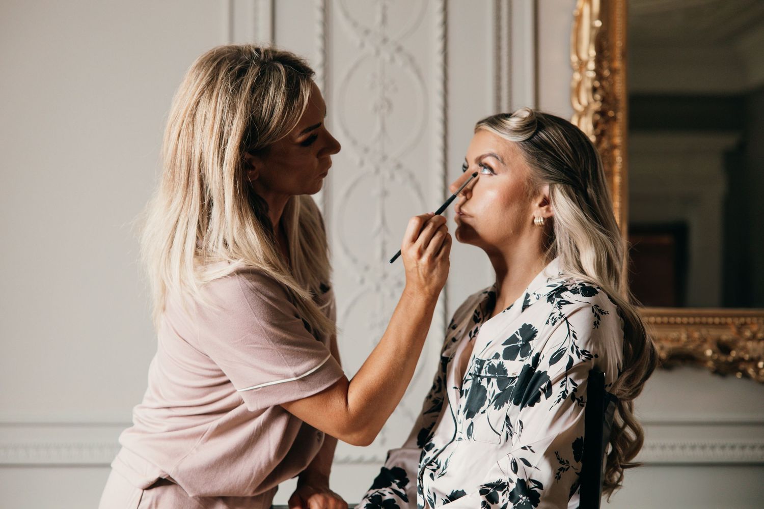 Wedding day makeup application in a bright, classically decorated room.