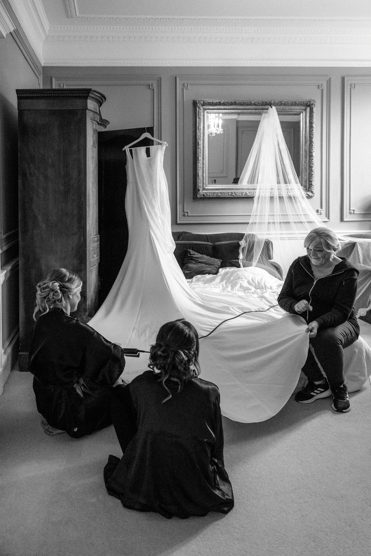Wedding dress and veil displayed in an elegant room as preparations take place.