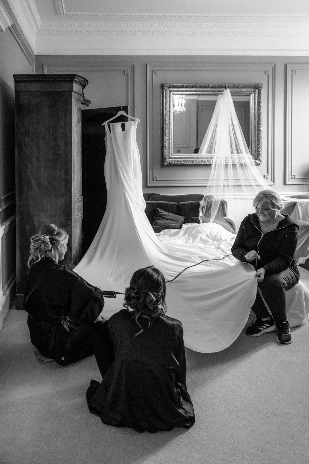 Wedding dress and veil displayed in an elegant room as preparations take place.